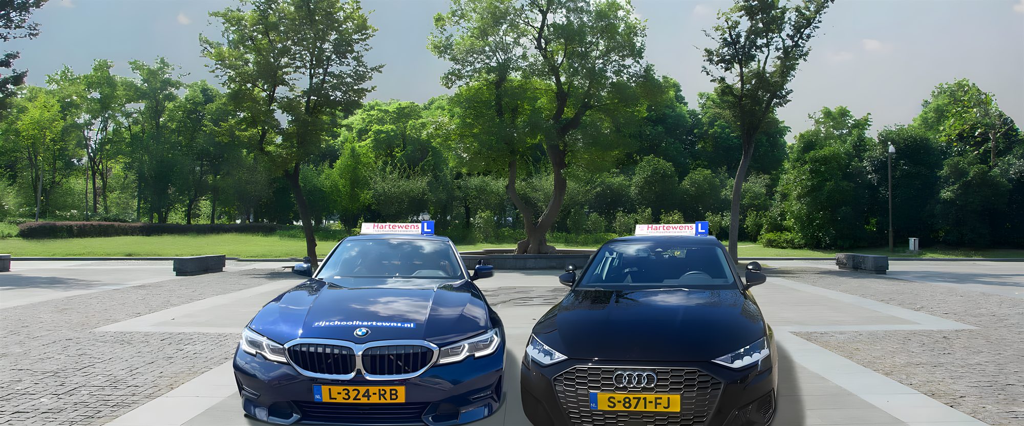 De twee lesauto's van Rijschool Hartewens naast elkaar: de blauwe BMW 3-serie en de zwarte Audi A3